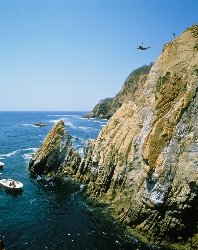 Cliff diver leaping from the rock face at La Quebrada, Acapulco
