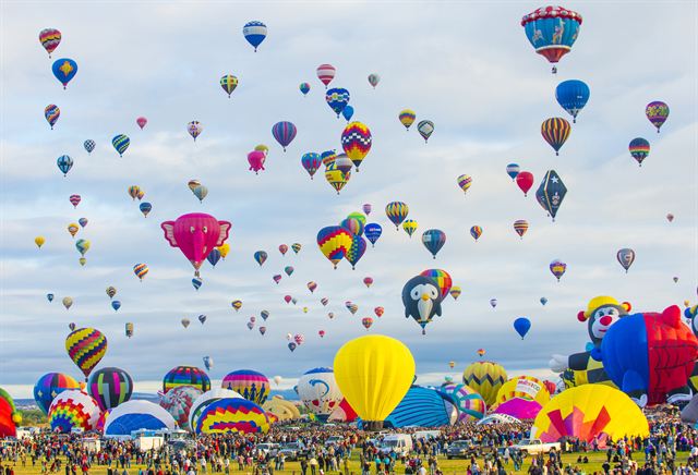 Mass ascension of balloons, including special shapes, over the Balloon Fiesta field
