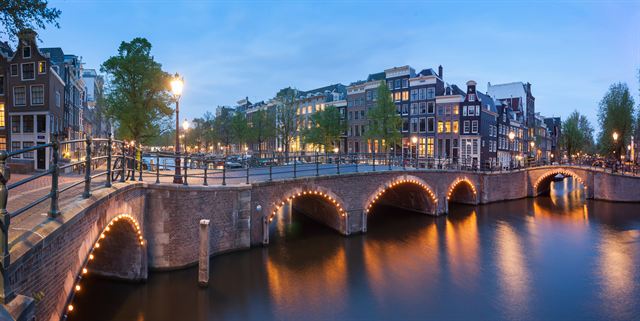 Amsterdam canal bridge and canal houses lit at dusk