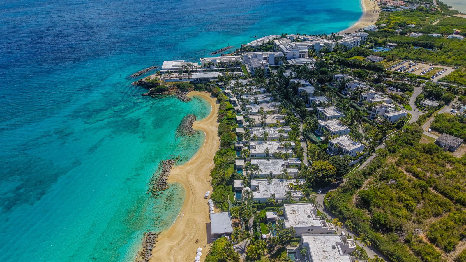 Aerial view of an Anguilla peninsula with a crescent beach, luxury resort villas and turquoise water
