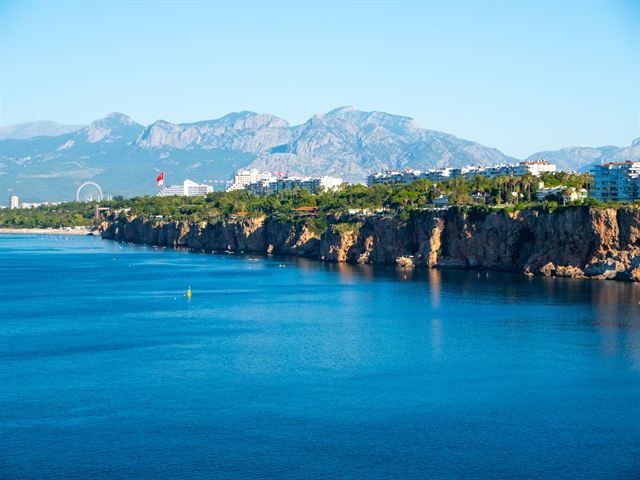 Antalya's sheer coastal cliffs above deep blue Mediterranean water with Taurus Mountains behind