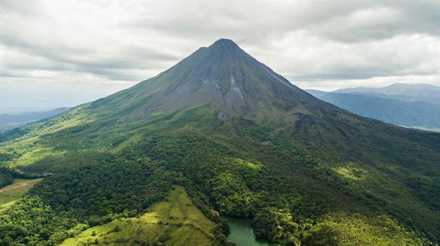 Aerial view of Arenal Volcano's green symmetrical slopes and surrounding rainforest in Costa Rica