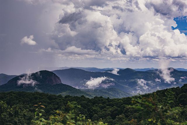 Forested Blue Ridge peaks and a granite dome under towering clouds in the mountains near Asheville