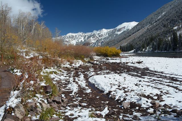 Snowy valley near Aspen, Colorado with autumn shrubs, evergreens and white peaks under blue sky