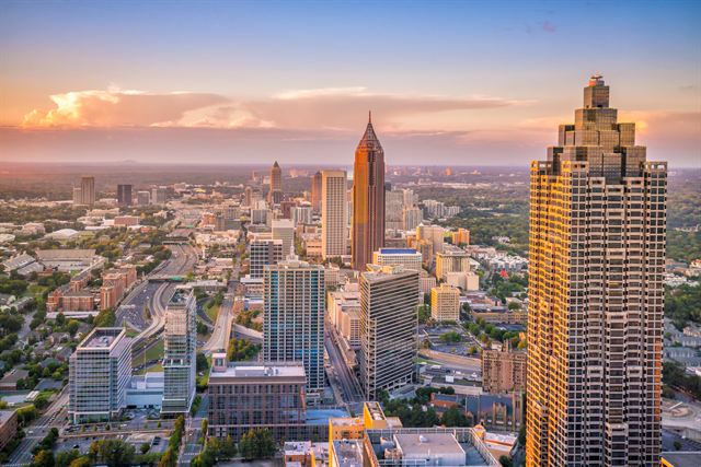 Aerial view of downtown and Midtown Atlanta skyscrapers, including the spired Bank of America Plaza, at sunset