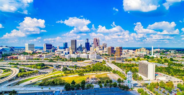 Drone panorama of the Atlanta skyline and freeway interchanges under a bright blue sky