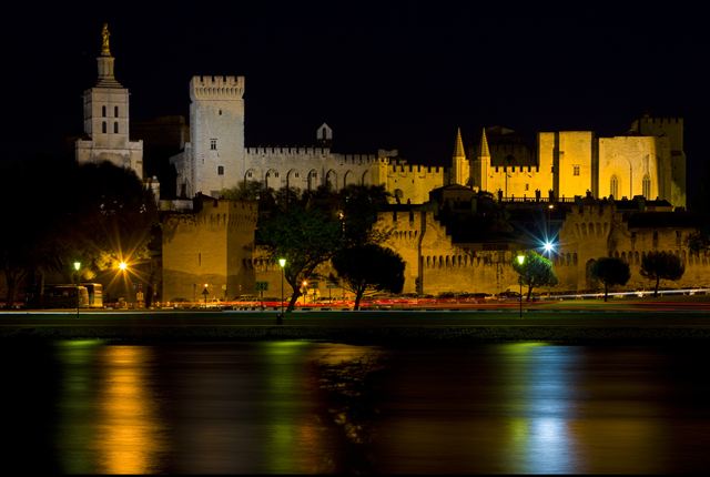 Floodlit Palais des Papes and Avignon cathedral reflected in the river at night