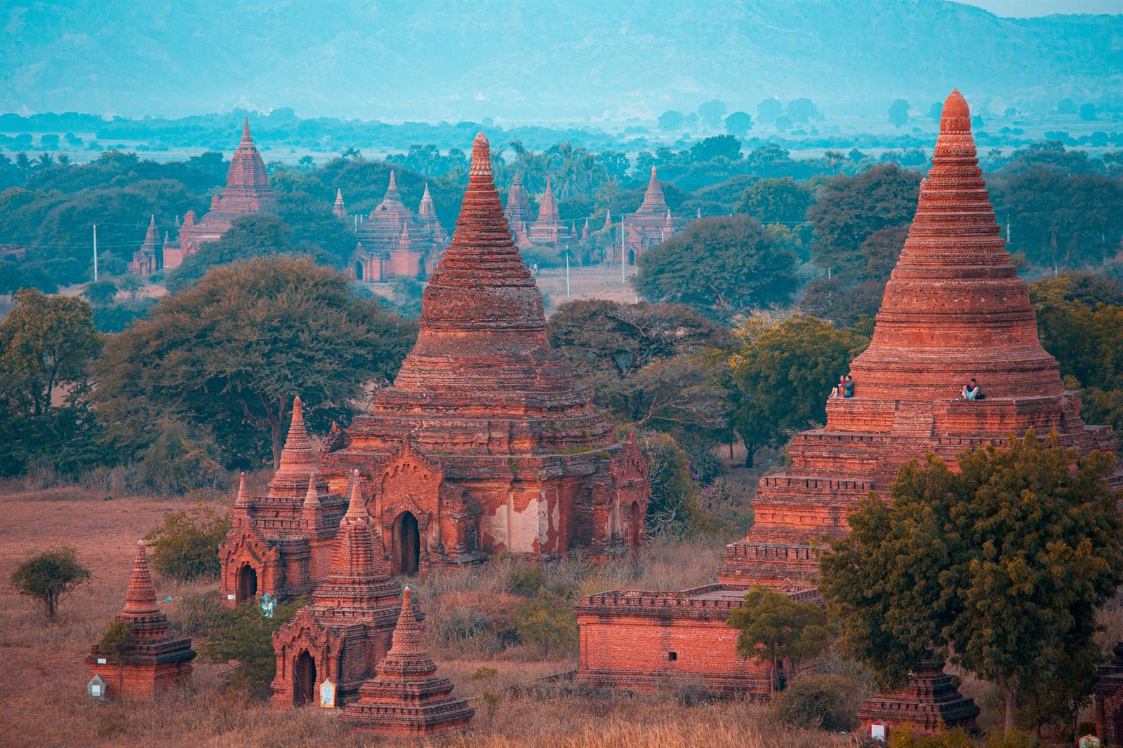 Red-brick temples and stupas of Bagan rising from green trees across the ancient plain