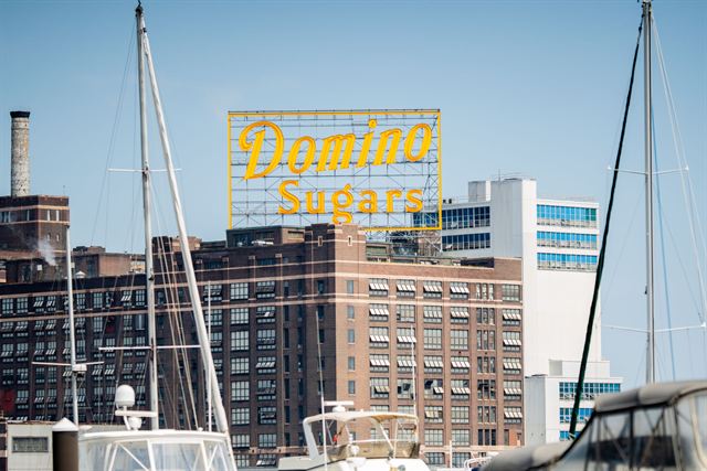 The landmark yellow Domino Sugars neon sign above the refinery by Baltimore harbor with boat masts