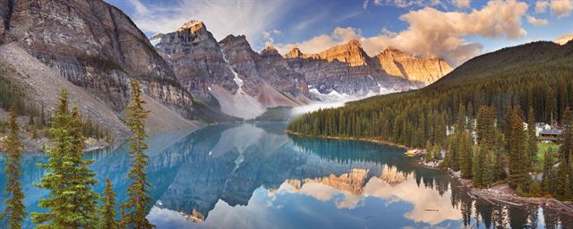 Panorama of Moraine Lake's still turquoise water reflecting the Valley of the Ten Peaks at sunrise