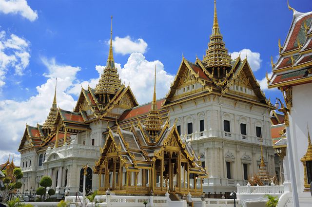 Gilded spires and roofs of the Grand Palace under a blue sky