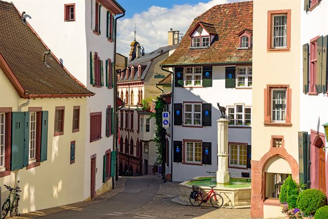 Winding cobbled street with medieval houses and a fountain in Grossbasel old town, Basel