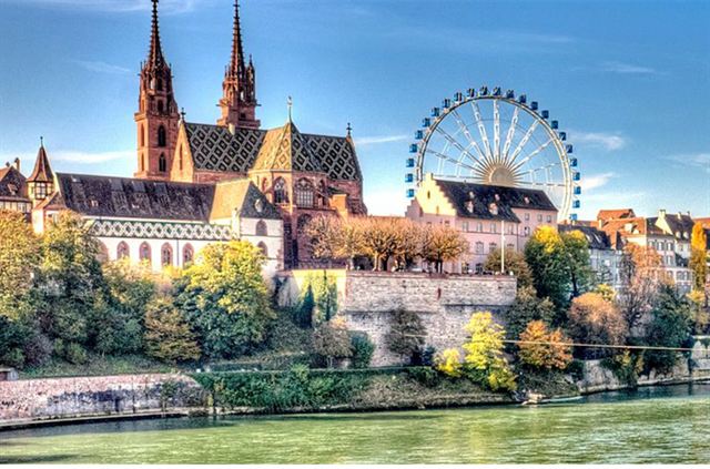 Red sandstone Basel Minster above the Rhine with a Ferris wheel on Munsterplatz behind