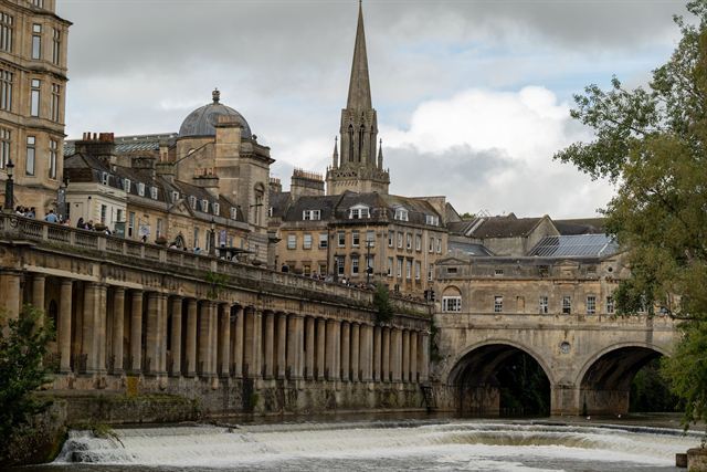 Pulteney Bridge and weir on the River Avon in Bath with Georgian colonnade and abbey spire