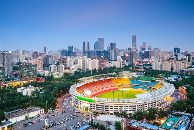 Aerial view of Beijing high-rises around the colorful Workers Stadium under a blue evening sky