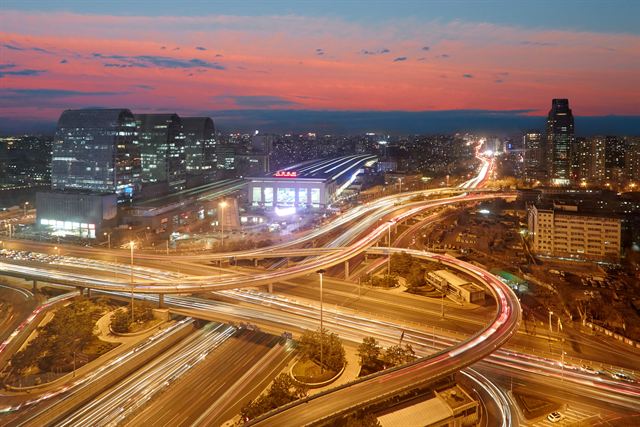 Beijing ring road interchange with light trails and office towers at dusk