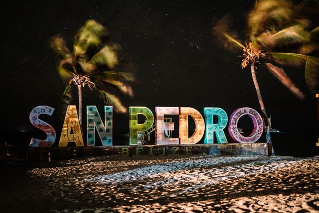 Colorful illuminated San Pedro Belize letters sign on the sand under palms and a starry night sky, Ambergris Caye