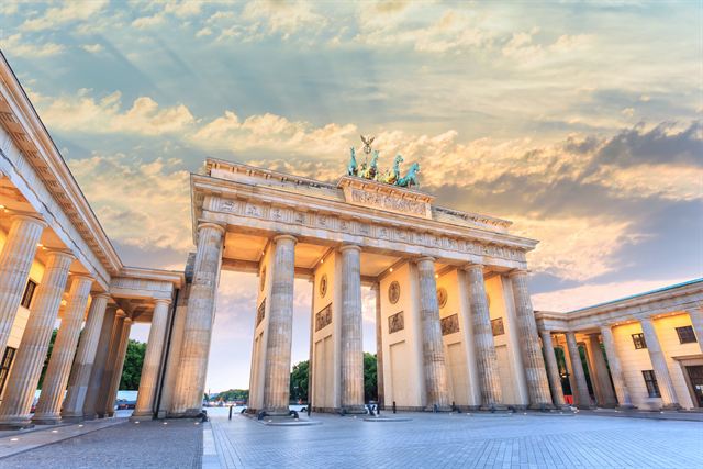 Brandenburg Gate columns and Quadriga statue against a dramatic sunset sky in Berlin