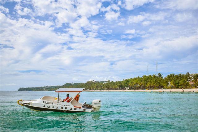 Speedboat on clear turquoise water off Boracay's palm-fringed white sand shore