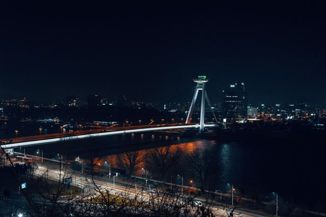 Most SNP bridge with its UFO tower lit over the Danube at night, seen from Bratislava Castle