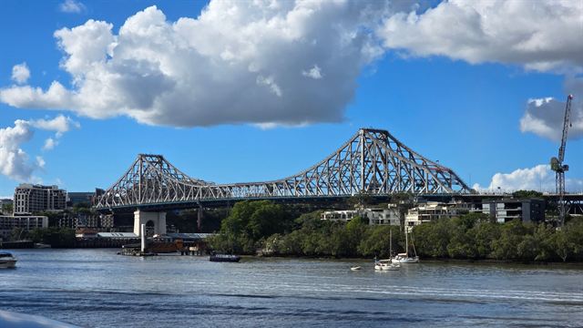 Steel cantilever Story Bridge spanning the Brisbane River under white clouds and blue sky