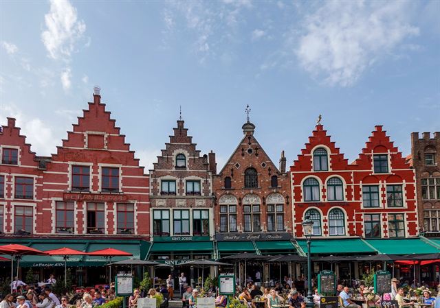 Colorful stepped-gable guild houses with cafe awnings lining the Markt (Market Square) in Bruges