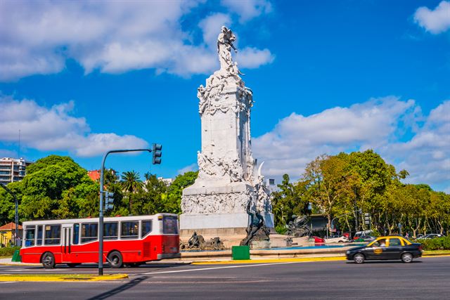 White Monument of the Spanish in Palermo, Buenos Aires, with a red city bus passing by