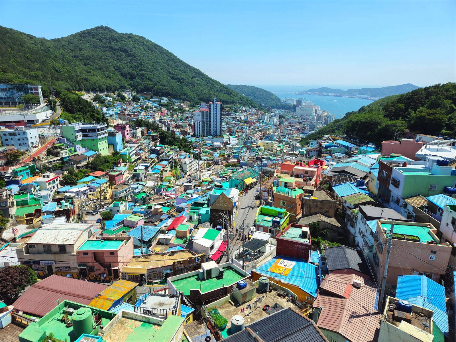 Aerial view of Gamcheon Culture Village's pastel hillside houses in Busan with the sea in the distance