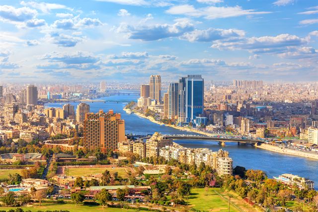 Aerial view of Cairo high-rises, bridges and the Nile river under a blue sky