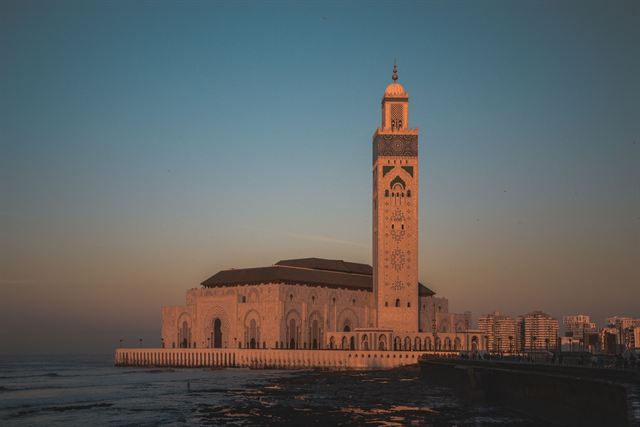 Hassan II Mosque minaret and prayer hall glowing at sunset above the Atlantic in Casablanca