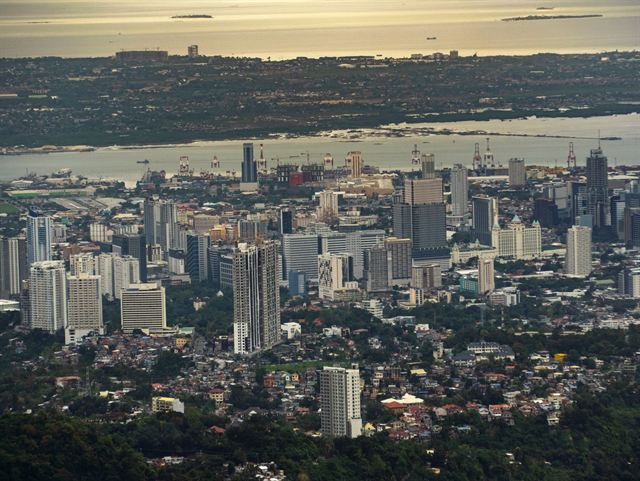 Cebu City skyline of high-rise towers spreading to the harbor and Mactan Channel, seen from the hills