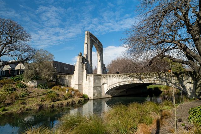 Bridge of Remembrance memorial arch over the Avon River in Christchurch among bare trees
