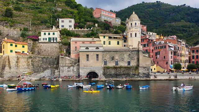 Vernazza harbor with Santa Margherita church tower, pastel buildings and small boats moored in the cove