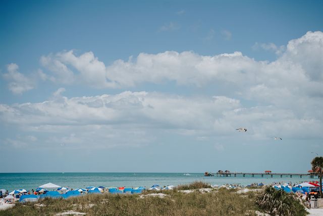 Clearwater Beach dunes and rows of blue umbrellas with Pier 60 reaching into the Gulf