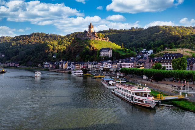 Reichsburg castle on its hill above Cochem, with river cruise boats on the Moselle