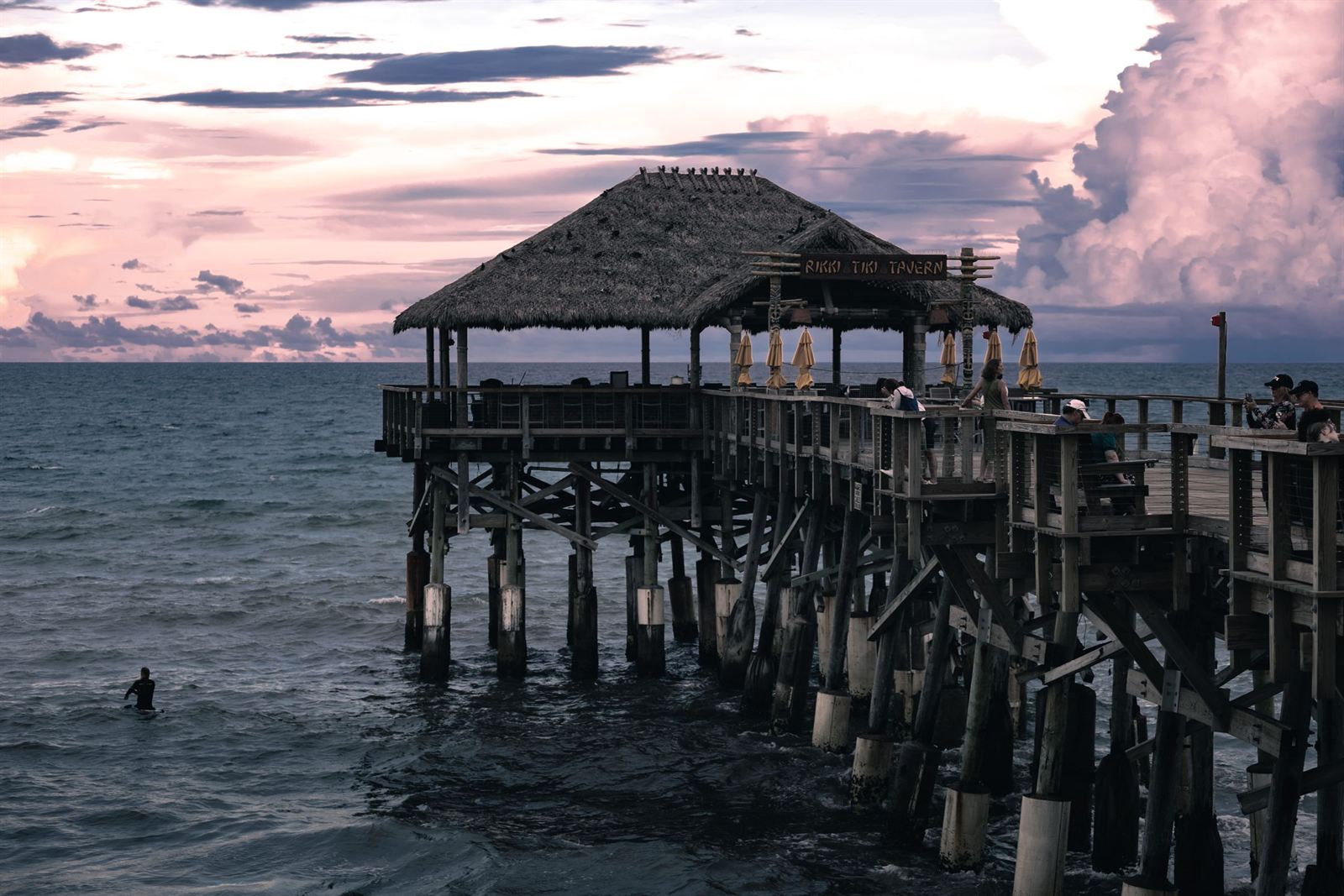 Cocoa Beach Pier with its thatched tiki hut over the Atlantic under a pink sunset sky