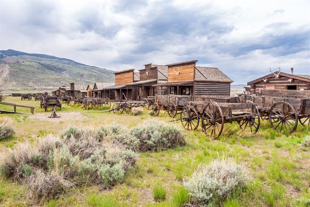 Weathered log buildings and wagons at Old Trail Town in Cody, Wyoming