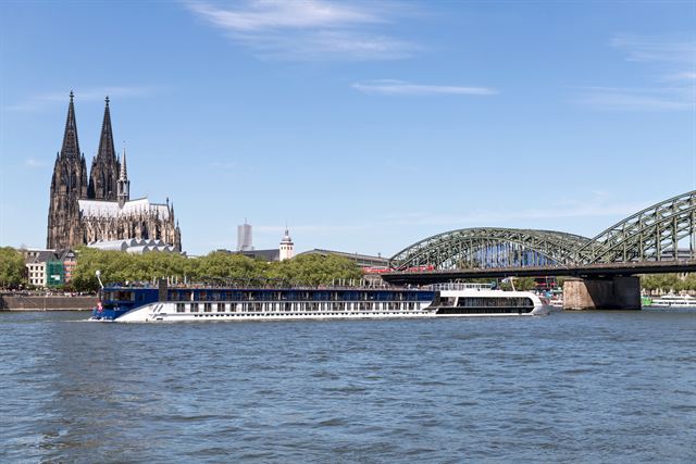 Cologne Cathedral and Hohenzollern Bridge above the Rhine with a river cruise ship
