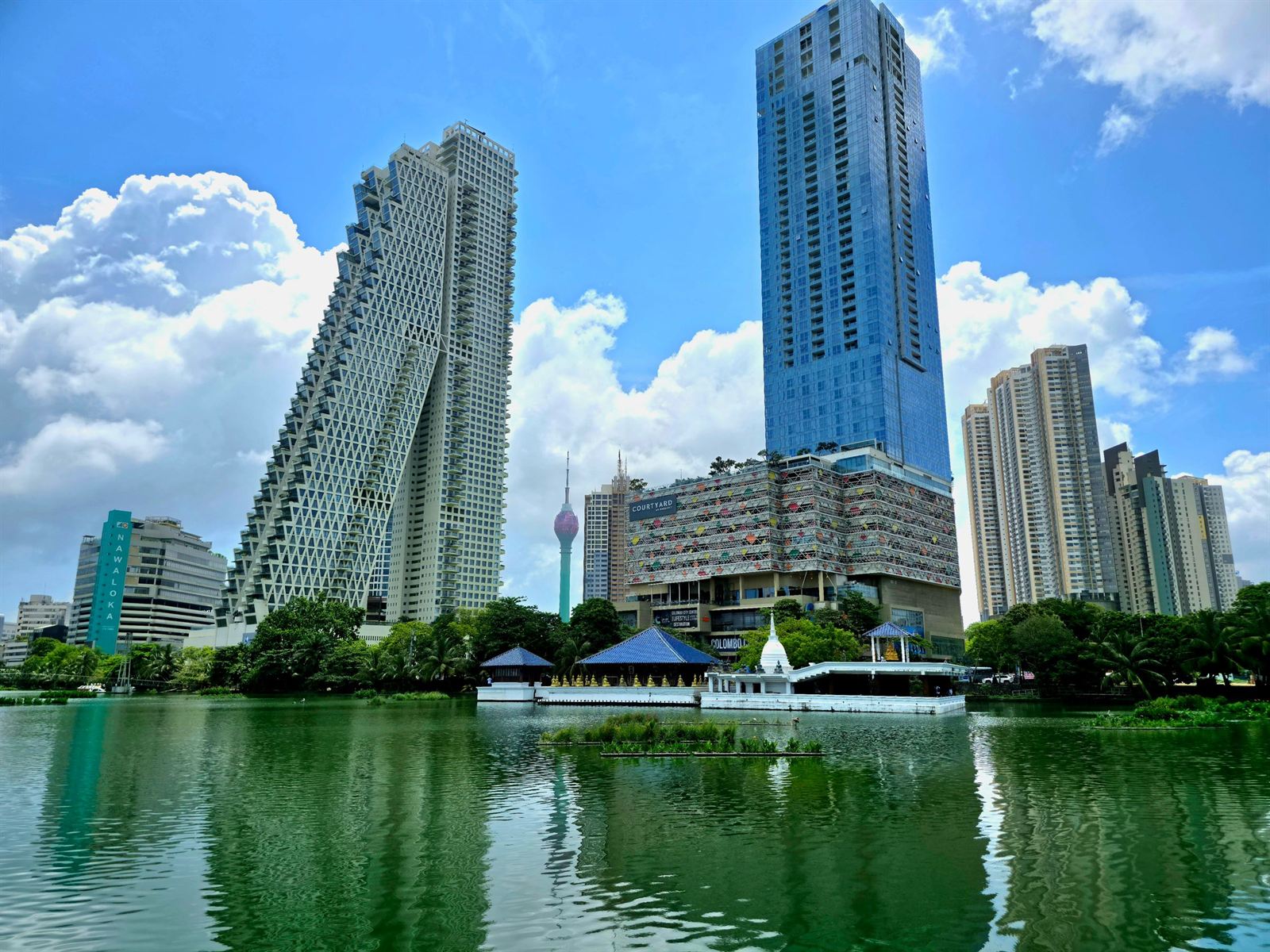Colombo's Altair towers and Lotus Tower rising over green Beira Lake under blue sky