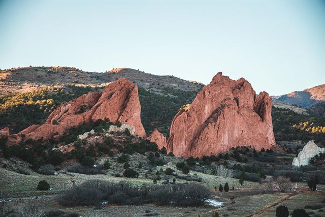Red sandstone fins of Garden of the Gods in Colorado Springs rising above green scrub and foothills
