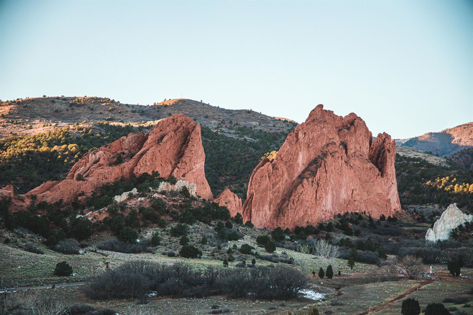 Red sandstone fins of Garden of the Gods in Colorado Springs rising above green scrub and foothills