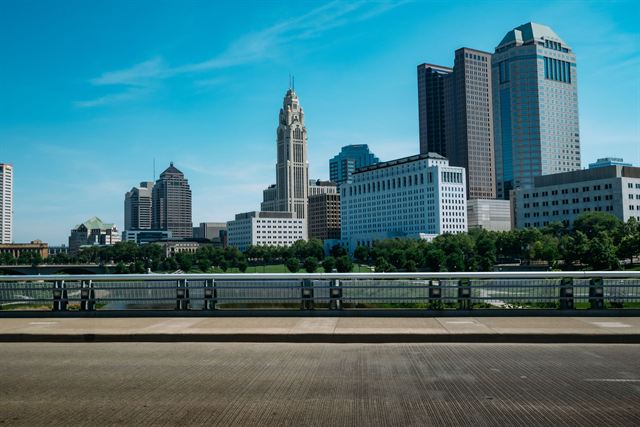 Columbus Ohio skyline including the LeVeque Tower seen from an open riverside plaza under blue sky