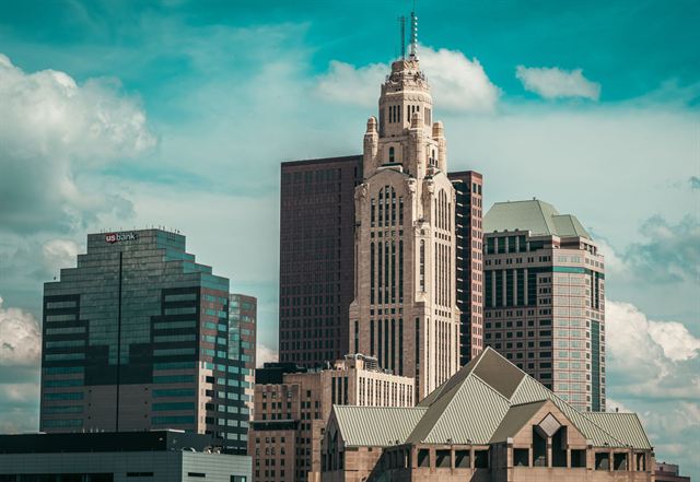Art Deco LeVeque Tower rising among downtown Columbus Ohio office buildings against a bright cloudy sky
