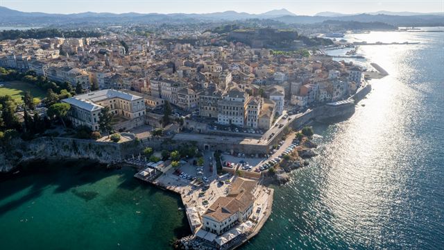 Aerial view of Corfu Old Town's dense historic buildings along the sunlit coast