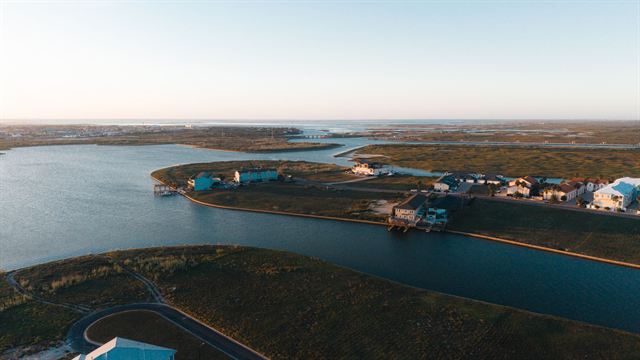Aerial view of waterfront homes along channels and marshland in Corpus Christi, Texas at sunset
