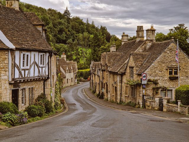 Winding lane through Castle Combe with half-timbered and Cotswold stone cottages
