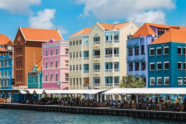 Pastel and bright Dutch colonial buildings with orange tile roofs on the Handelskade waterfront in Willemstad