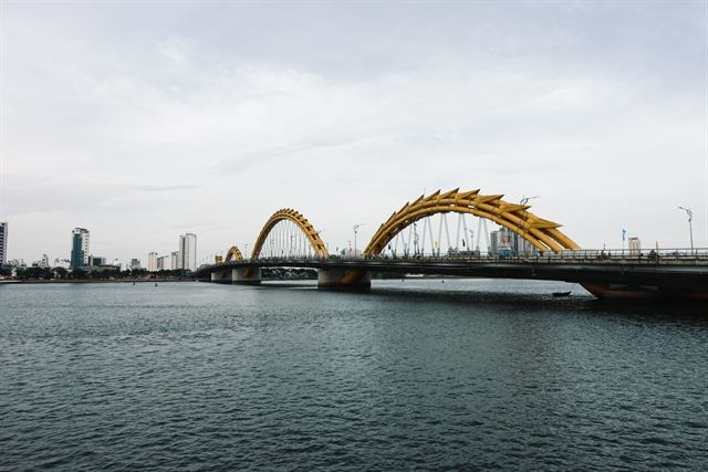 Golden Dragon Bridge arching over the Han River in Da Nang with city skyline beyond