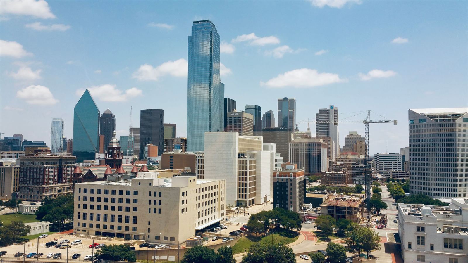 Downtown Dallas skyline of glass skyscrapers including Bank of America Plaza under a bright blue sky