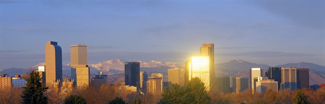 Denver skyline with glowing glass towers and the Rocky Mountains behind, Colorado